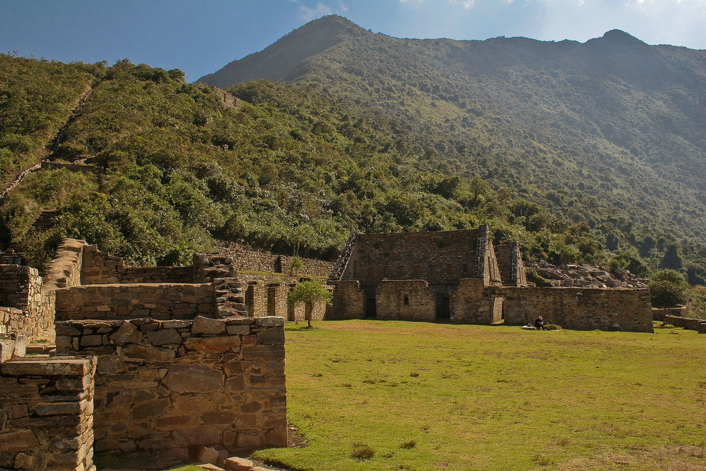 Ancient stone ruins in a lush green landscape with mountains in the background