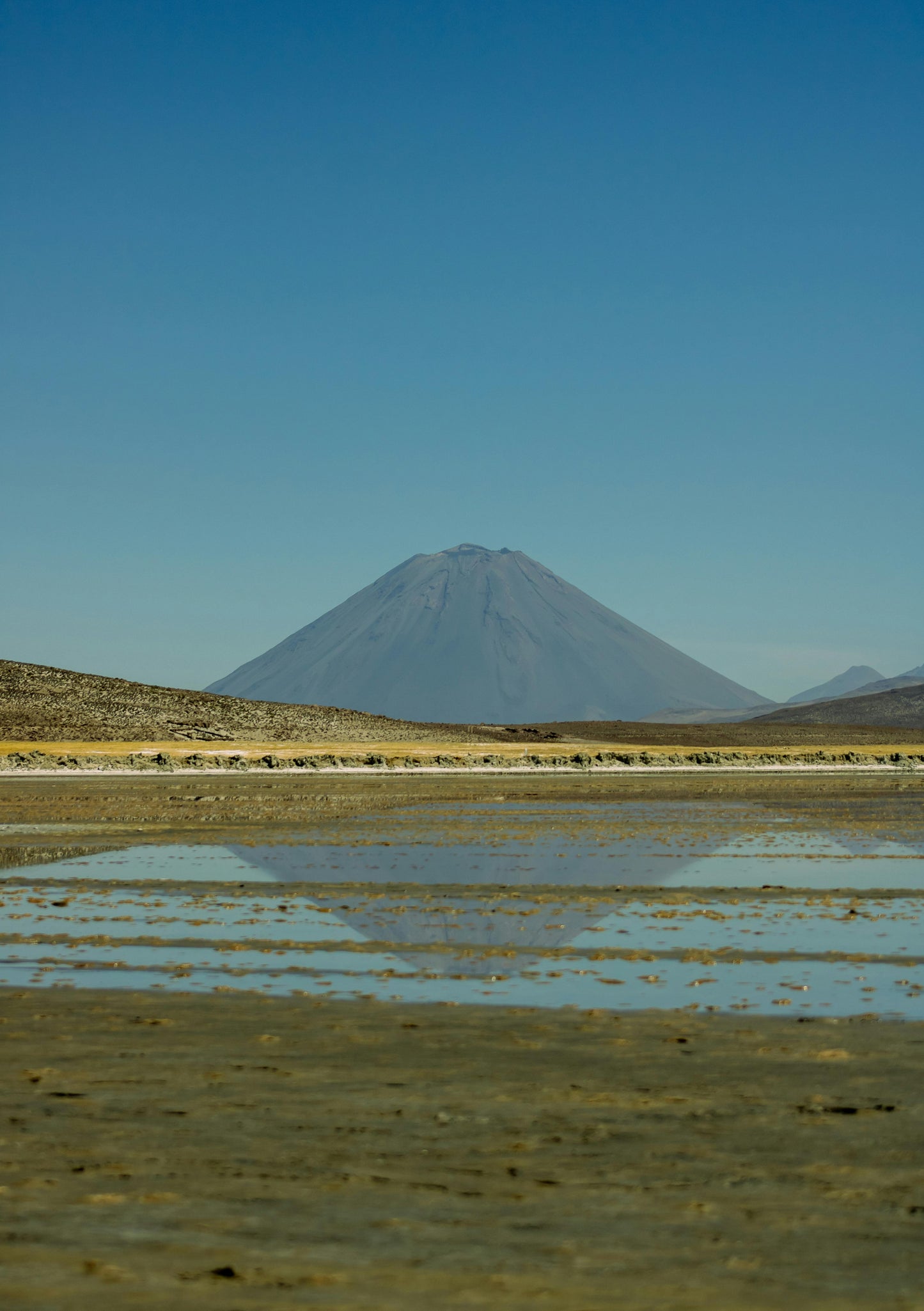 Mountain reflected in a body of water with clear blue sky