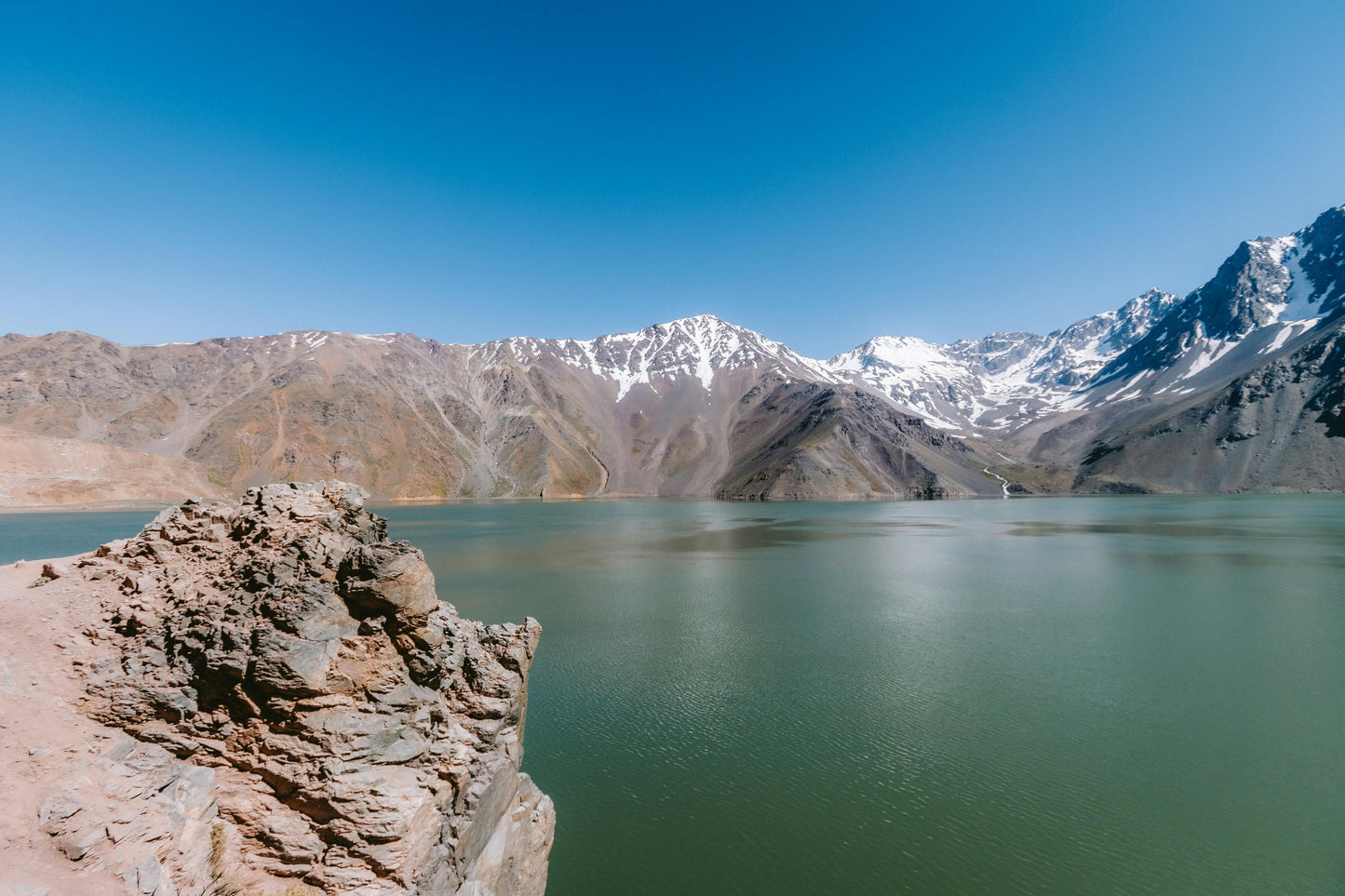 Mountain lake with snow-capped peaks under a clear blue sky