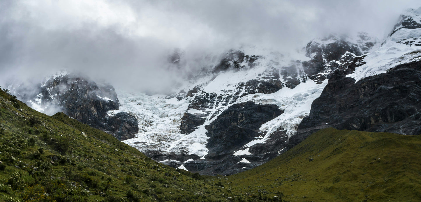Snow-capped mountains with green valleys on a cloudy day