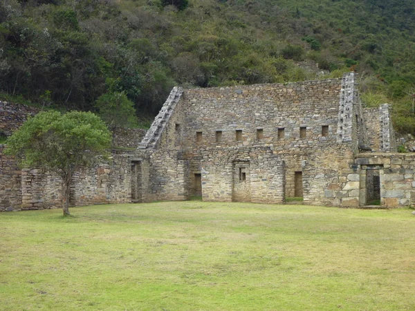 Stone building in a grassy area with trees in the background