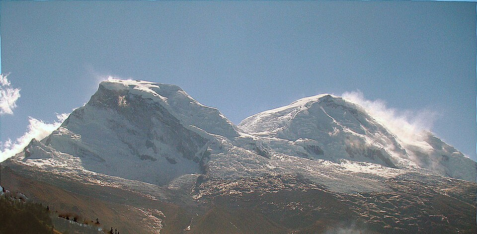 Two snow-capped mountains with a clear blue sky above.