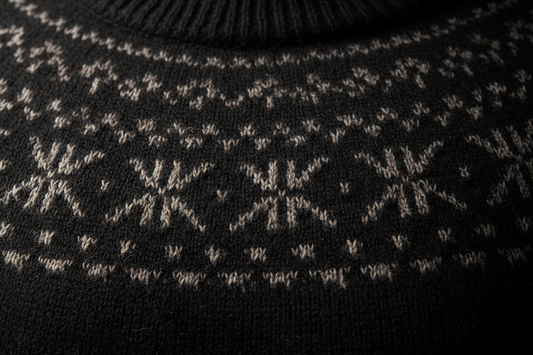Create a macro photo of the Nordic Alpaca Sweater – Black (#1A1A1A) showing the jacquard weave and Baby Alpaca fiber texture. Focus on the upper chest and collar area. Lighting should highlight the fiber softness and density. Output: square 2048x2048 px.
