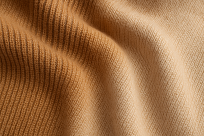 Generate a photorealistic image of a medium-weight alpaca knit, showing a balanced texture between warmth and flexibility.
Use warm camel, vicuña, and cream tones.
The knit should appear structured yet soft, ideal for classic sweaters and scarves.
Include visible stitch details like rib or plain knit pattern for authenticity.
Keywords: medium weight alpaca knit, versatile texture, alpaca sweater fabric, natural wool blend, wholesale alpaca textiles.