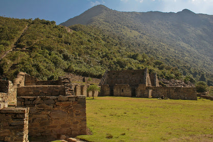 Ancient stone ruins in a lush green landscape with mountains in the background