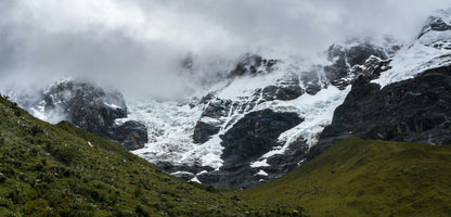 Snow-capped mountains with green valleys on a cloudy day