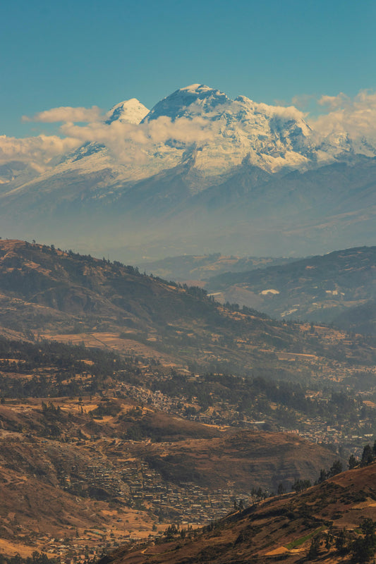 Snow-capped mountain peak with a valley below under a clear blue sky