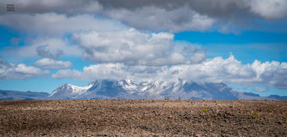 Scenic view of snow-capped mountains under a blue sky with clouds