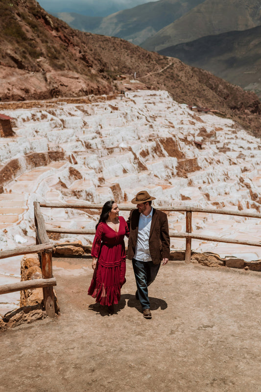 Two people walking on a path with terraced salt mines in the background